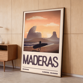 Print leaning on a floor depicting a minimalist illustration of a surfer with surfboard in warm sunset shades next to a mid-century wooden