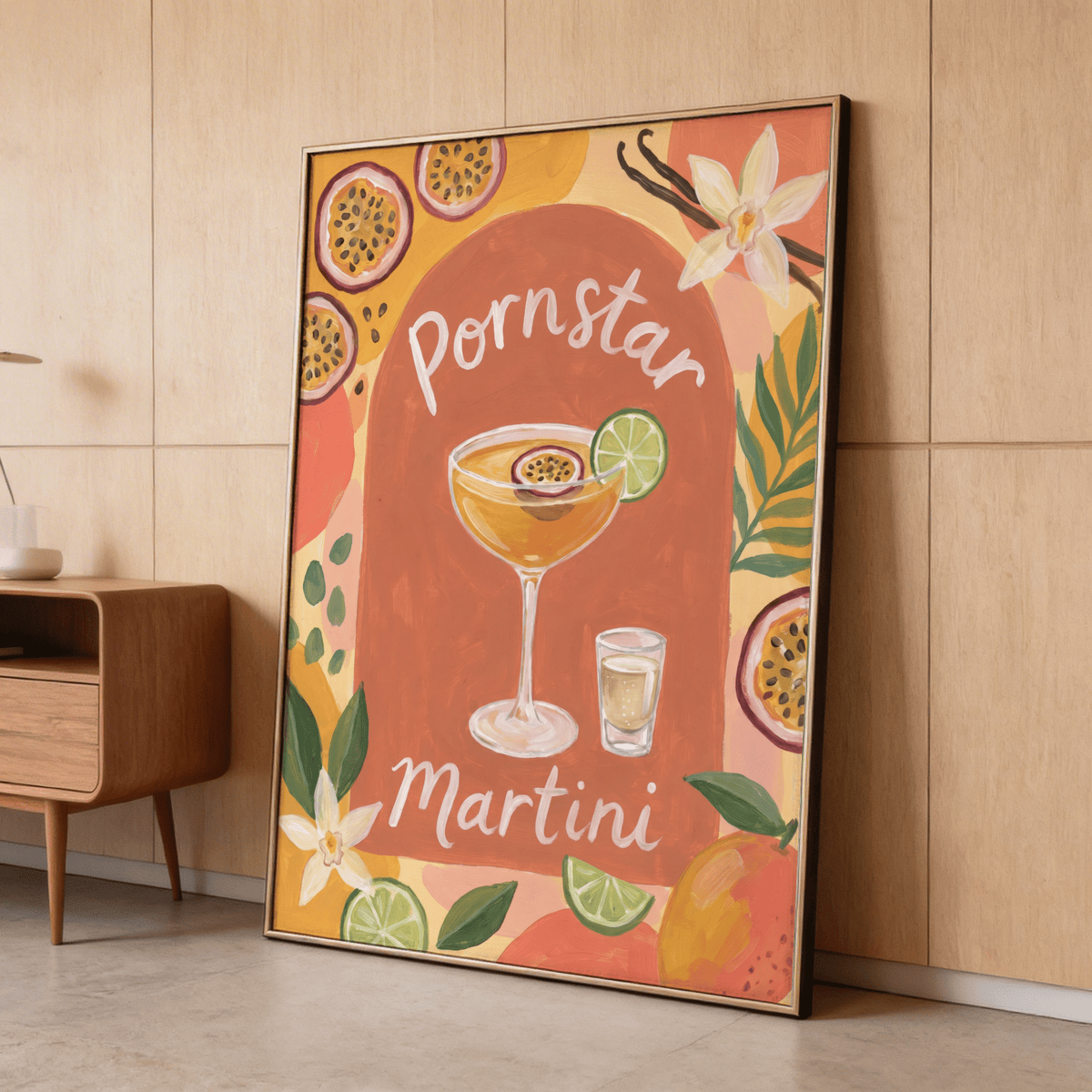 Framed Passion Fruit Martini Poster leaning on a floor with brown wall and wooden cabinet