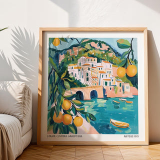 Print leaning on floor of Amalfi Coast Painting showing coastal town with citrus in soft blue and orange tones near a sofa