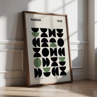 Gallery print leaning on floor with geometric abstract shapes in black and muted green in sunlight