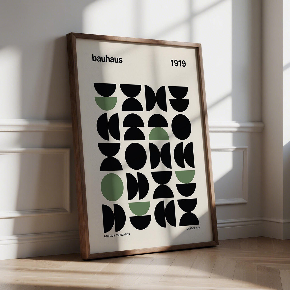 Gallery print leaning on floor with geometric abstract shapes in black and muted green in sunlight