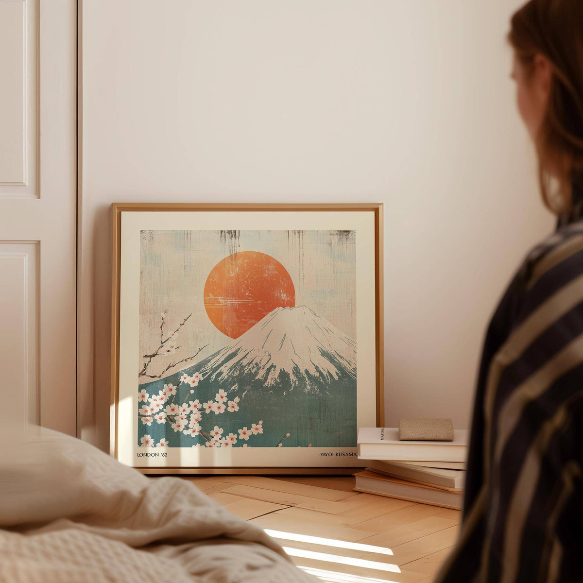 Square Print of Mount Fuji with pink cherry blossoms leaning on floor beside books