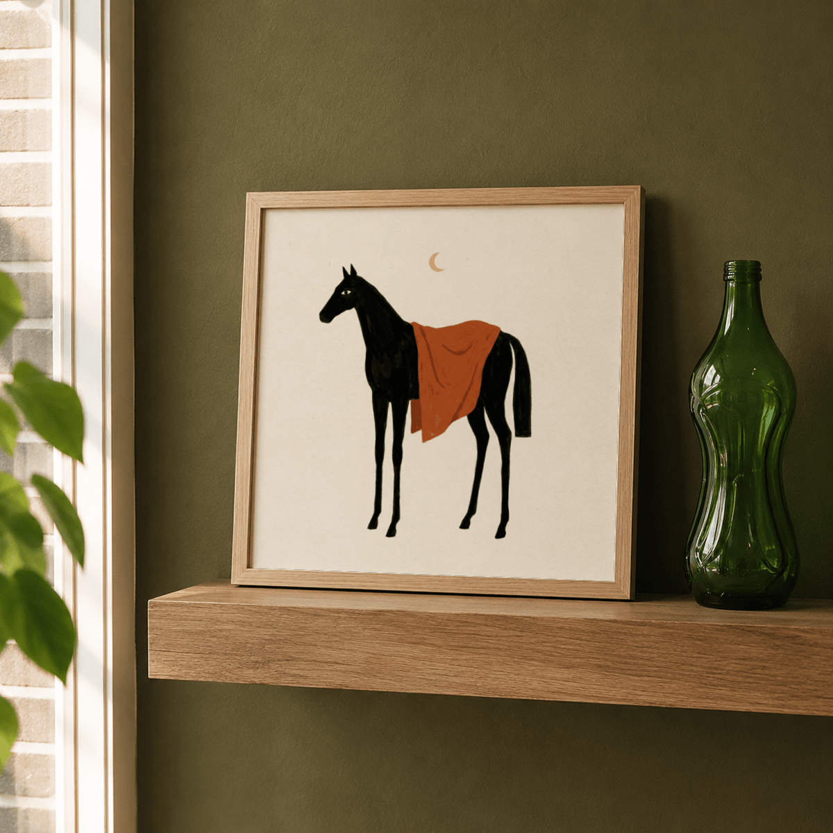 Framed Horse Moon wall art of a black horse with an orange blanket leaning on a wooden shelf next to a green bottle