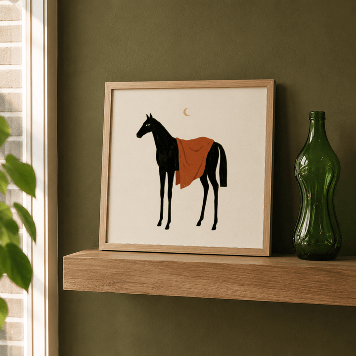Framed Horse Moon wall art of a black horse with an orange blanket leaning on a wooden shelf next to a green bottle