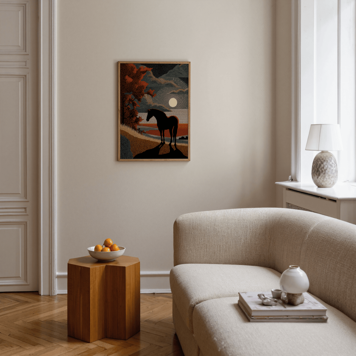 Print on a wall in a living room with horse silhouette art showing dusk colours and a round moon above a wooden side table