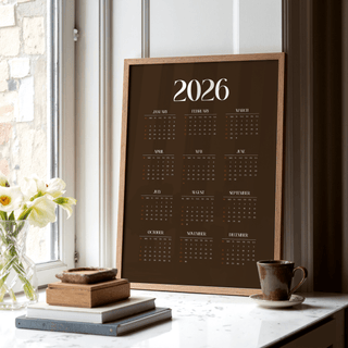Brown Calendar Print leaning on a window sill with books and a cup nearby in a bright space