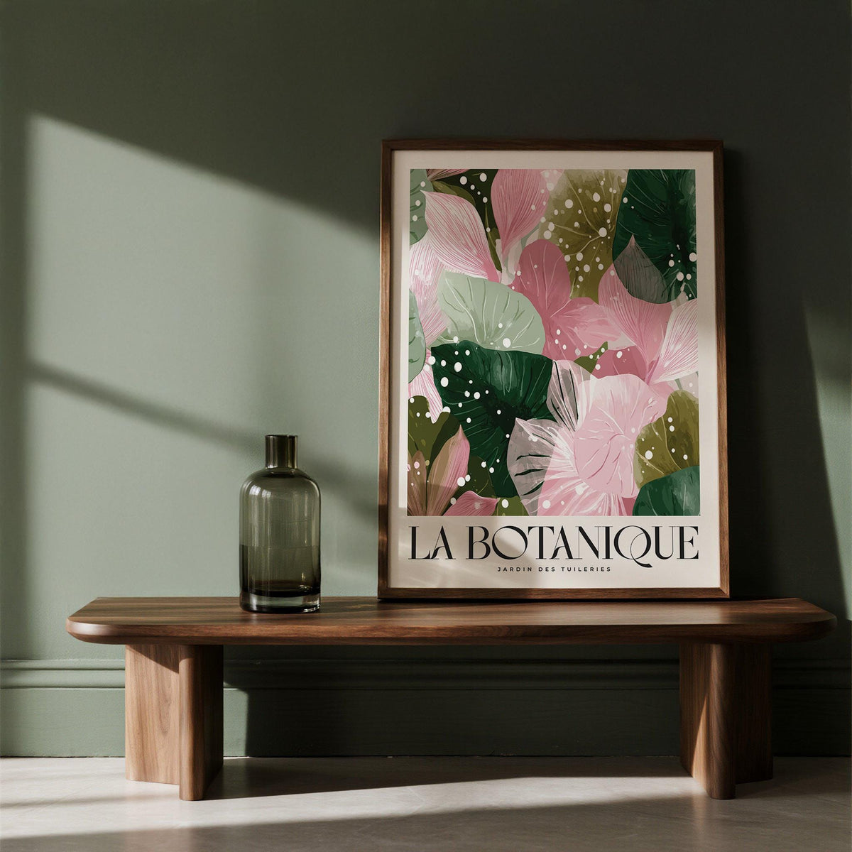 Framed print of decorative botanical leaves with pink and green tones on a wooden shelf with a glass vase