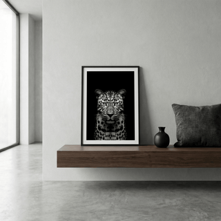 Black Leopard Art Print leaning on a wooden shelf with a black vase and cushion in a minimalist grey room