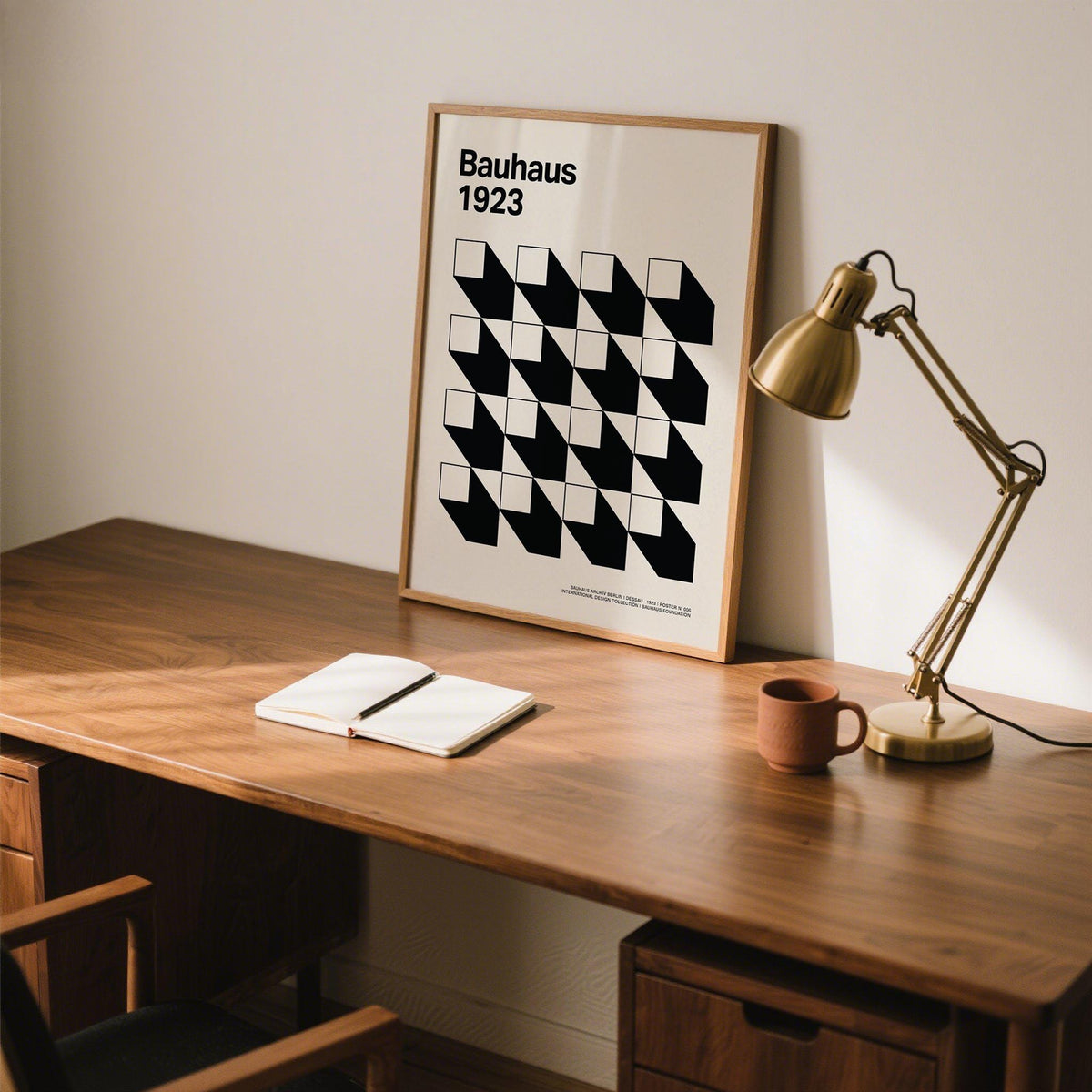Office Space Poster leaning on desk with black and white geometric shapes beside a brass desk lamp and terracotta mug