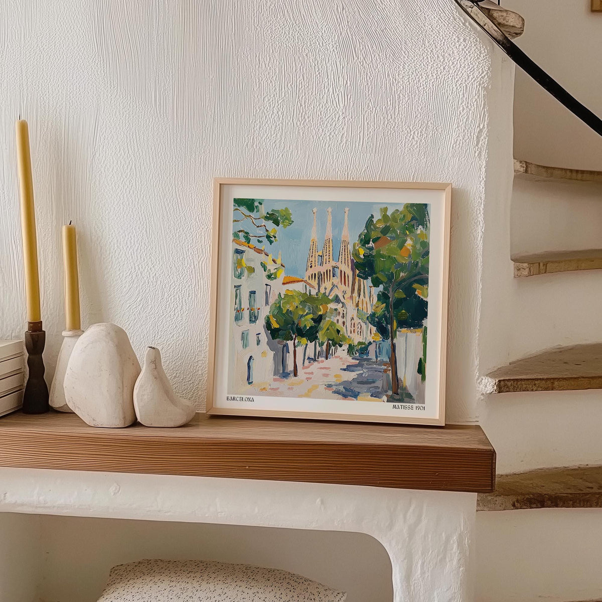 Framed Barcelona Boulevard Poster leaning on a wooden shelf with candles and decorative stones nearby
