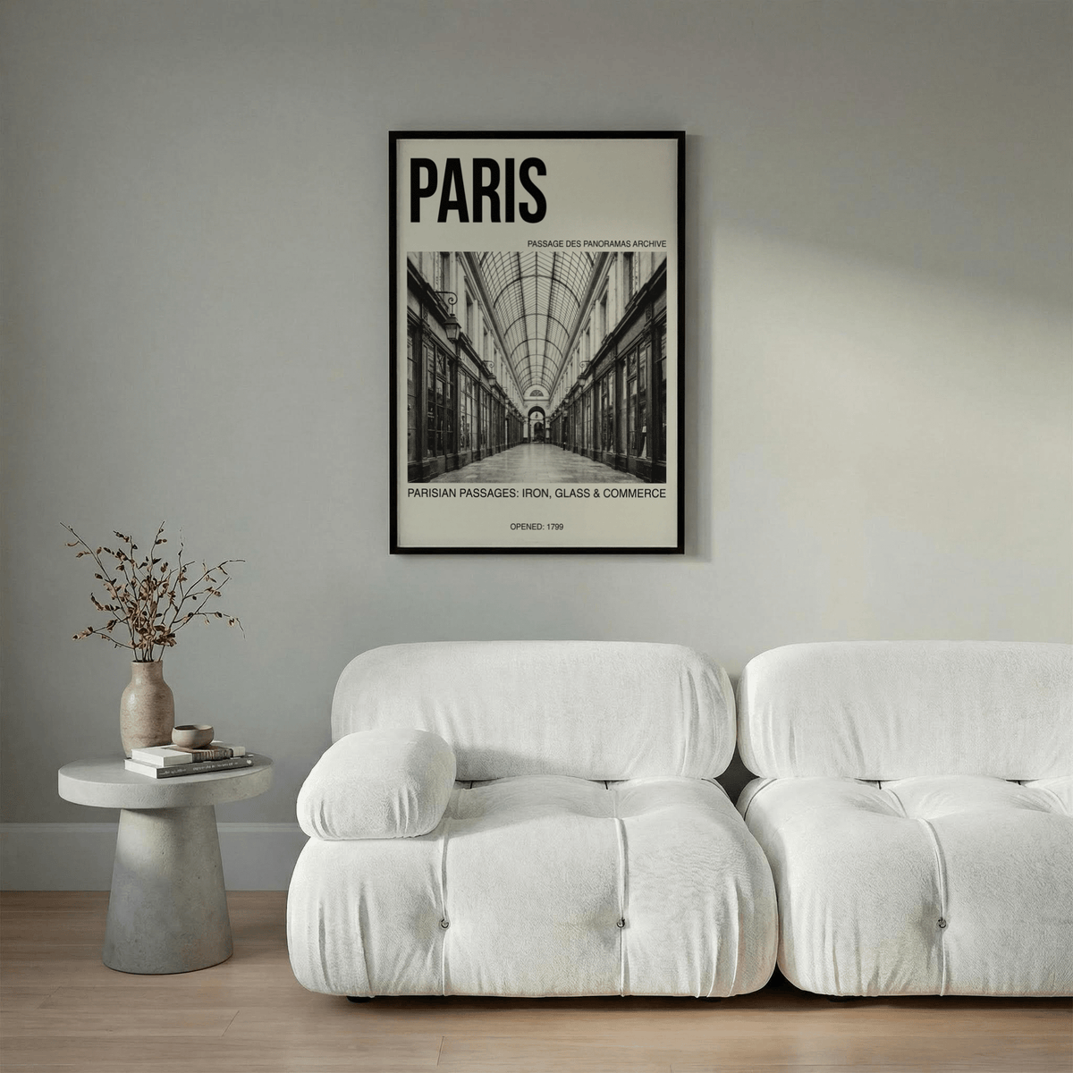 Parisian Passage Art Print above a white sofa with a minimalist side table and dried flowers