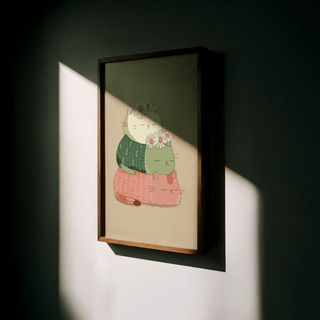 Framed Cute Cat Art Print with stacked cats in green and pink and daisies lit by sunlight on wall