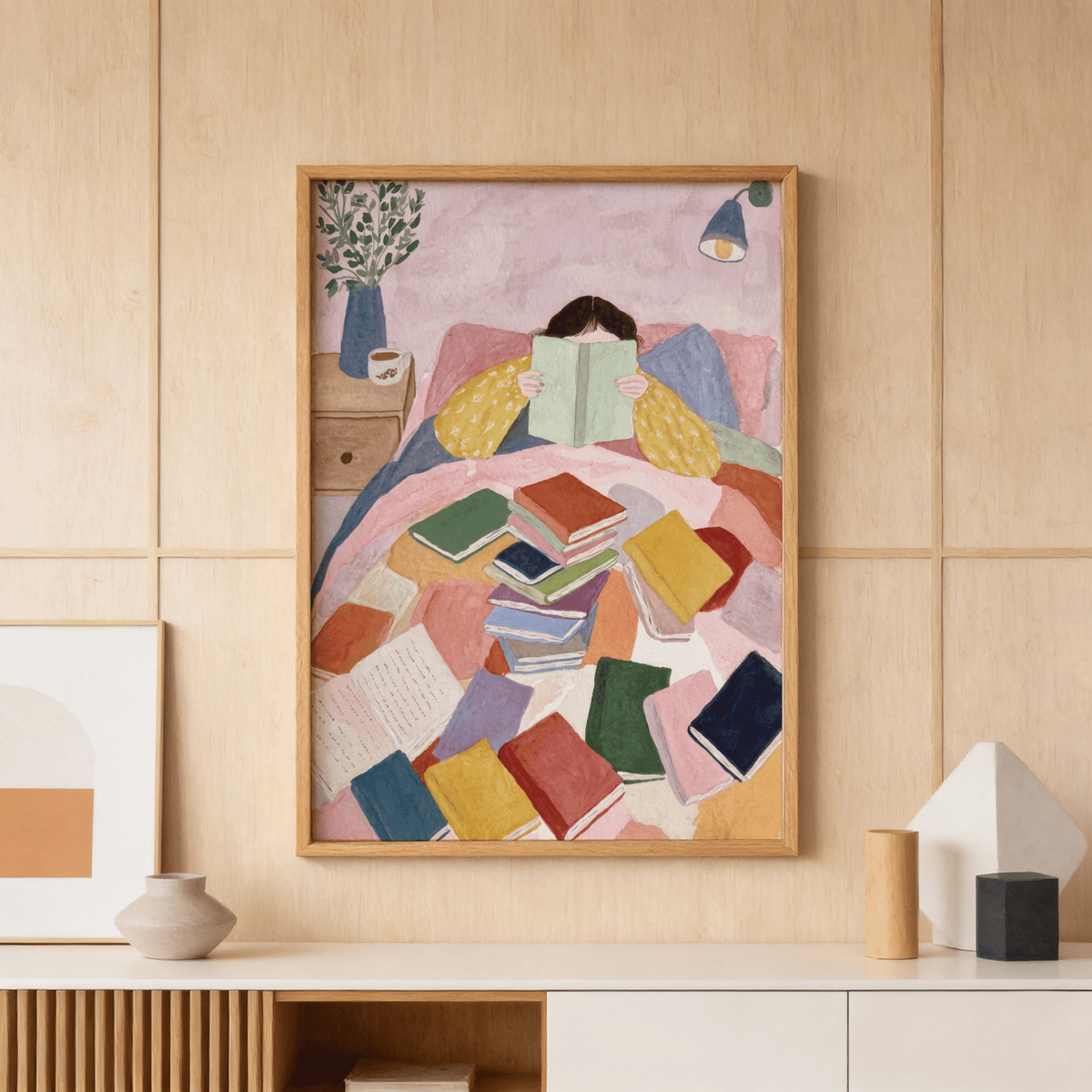 Framed Woman Reading In Bed Art Print with watercolour style and colourful books displayed on a wooden wall