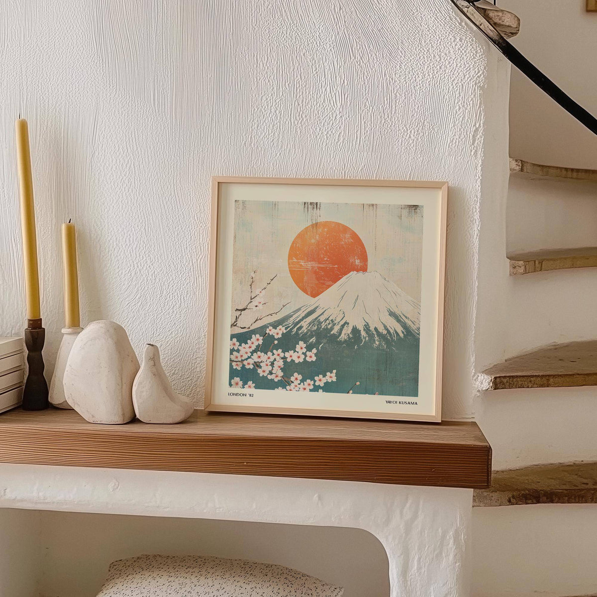 Square print of Mount Fuji with cherry blossoms in Japanese-woodblock style on a wooden shelf with candlesticks