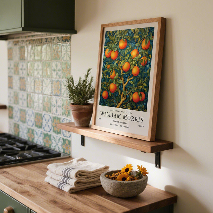 Orange Tree wall art leaning on shelf with a potted rosemary plant in a kitchen
