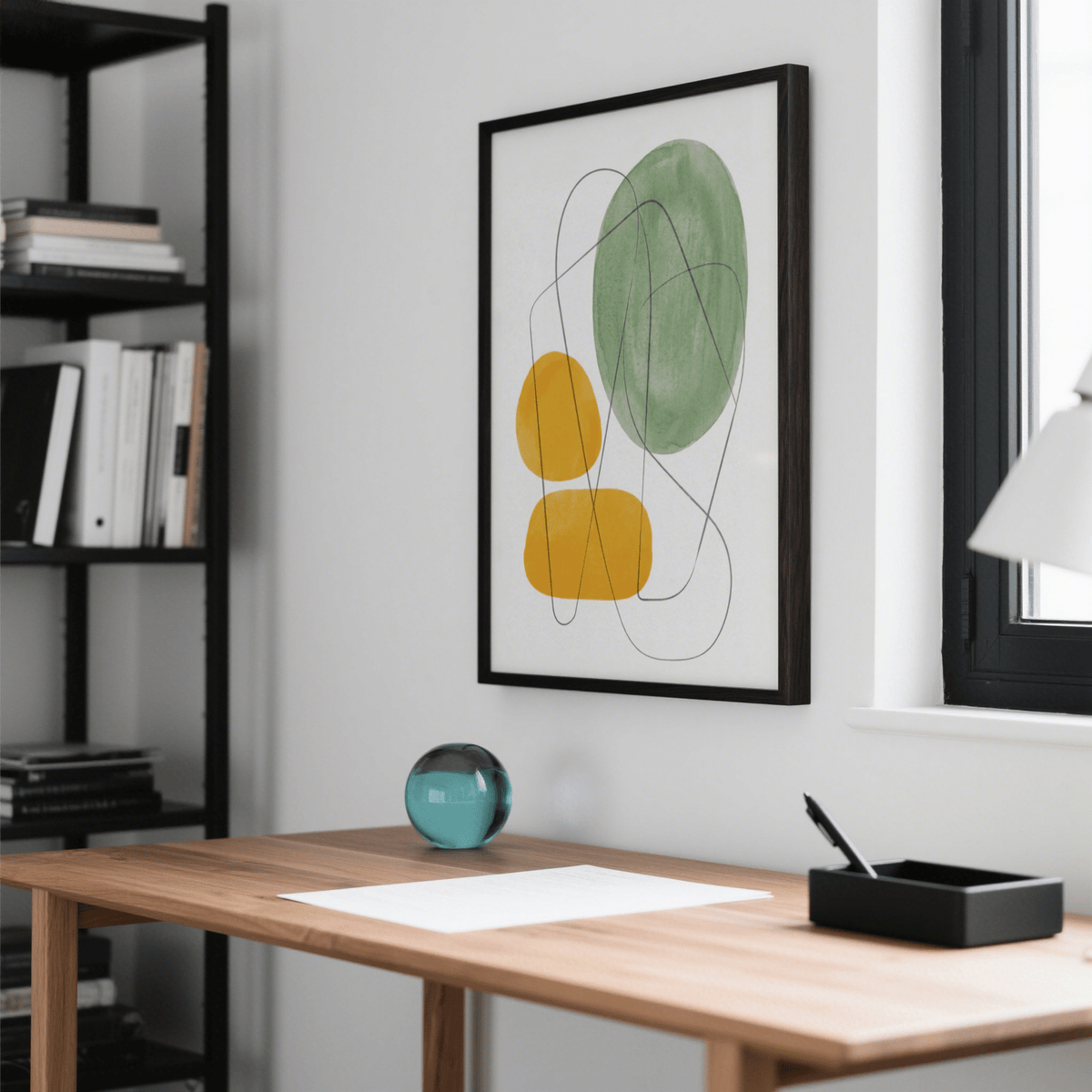 Yellow and Green Print of abstract organic shapes in green and yellow above a wooden desk with a glass orb