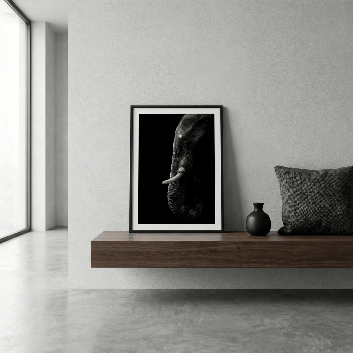 Print leaning on a shelf of a black elephant wall art featuring a minimalist photographic elephant head in black and grey with a small