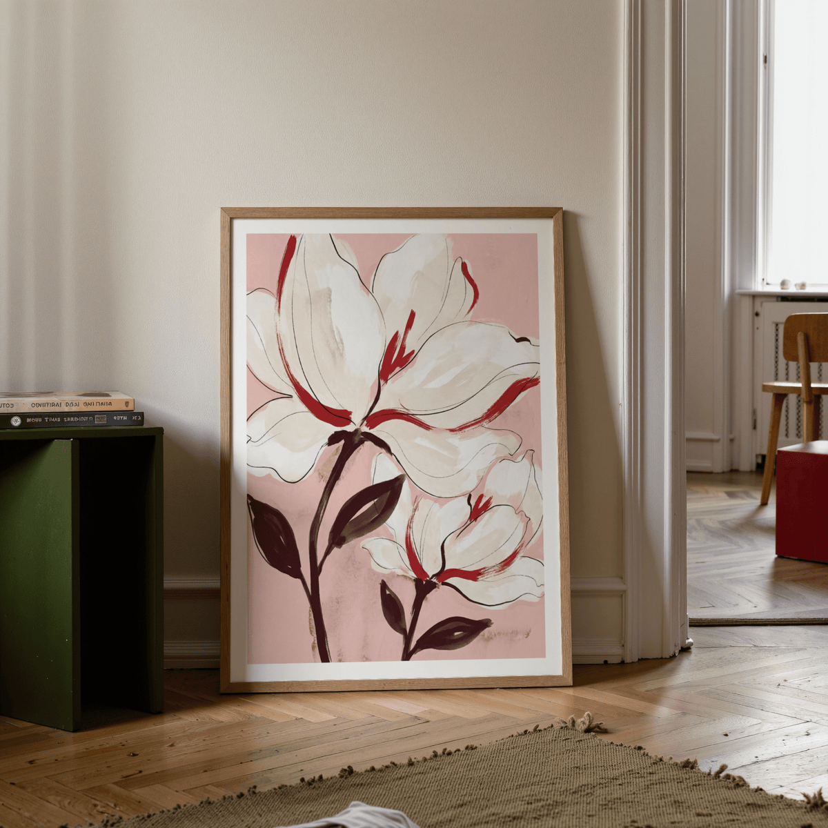 Flower print leaning on floor with white magnolia flowers in soft pink and red tones next to green stool