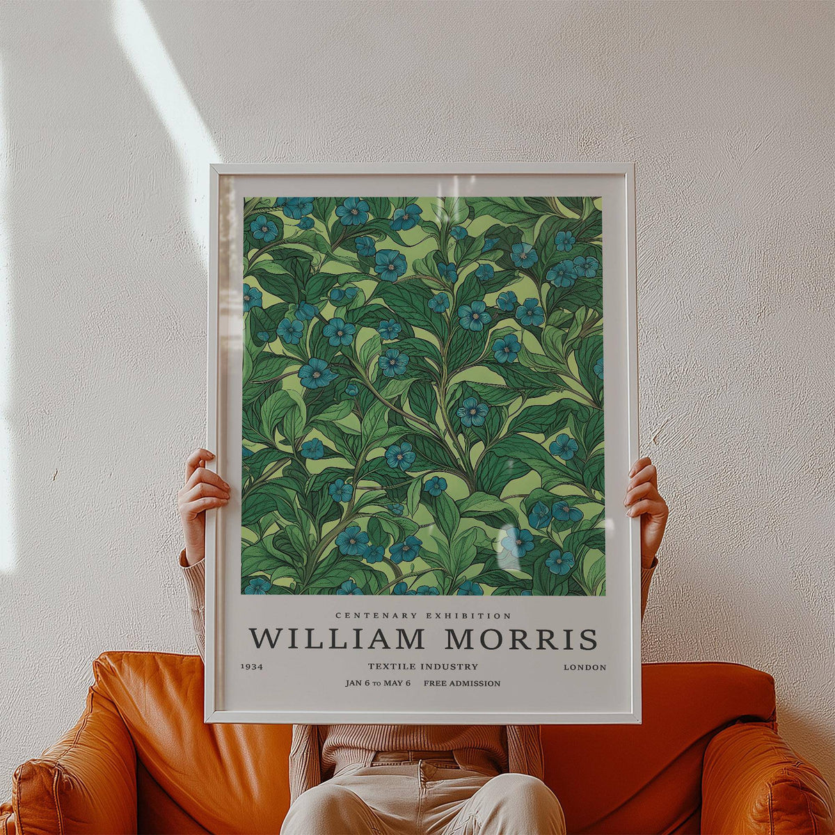 Framed Green Wall Art for Living Room showing blue flowers and green leaves held in hands above a brown leather chair