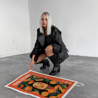 Cool Wall Art print on the floor showing a woman with orange slices in vibrant orange and green colours with a woman in black boots