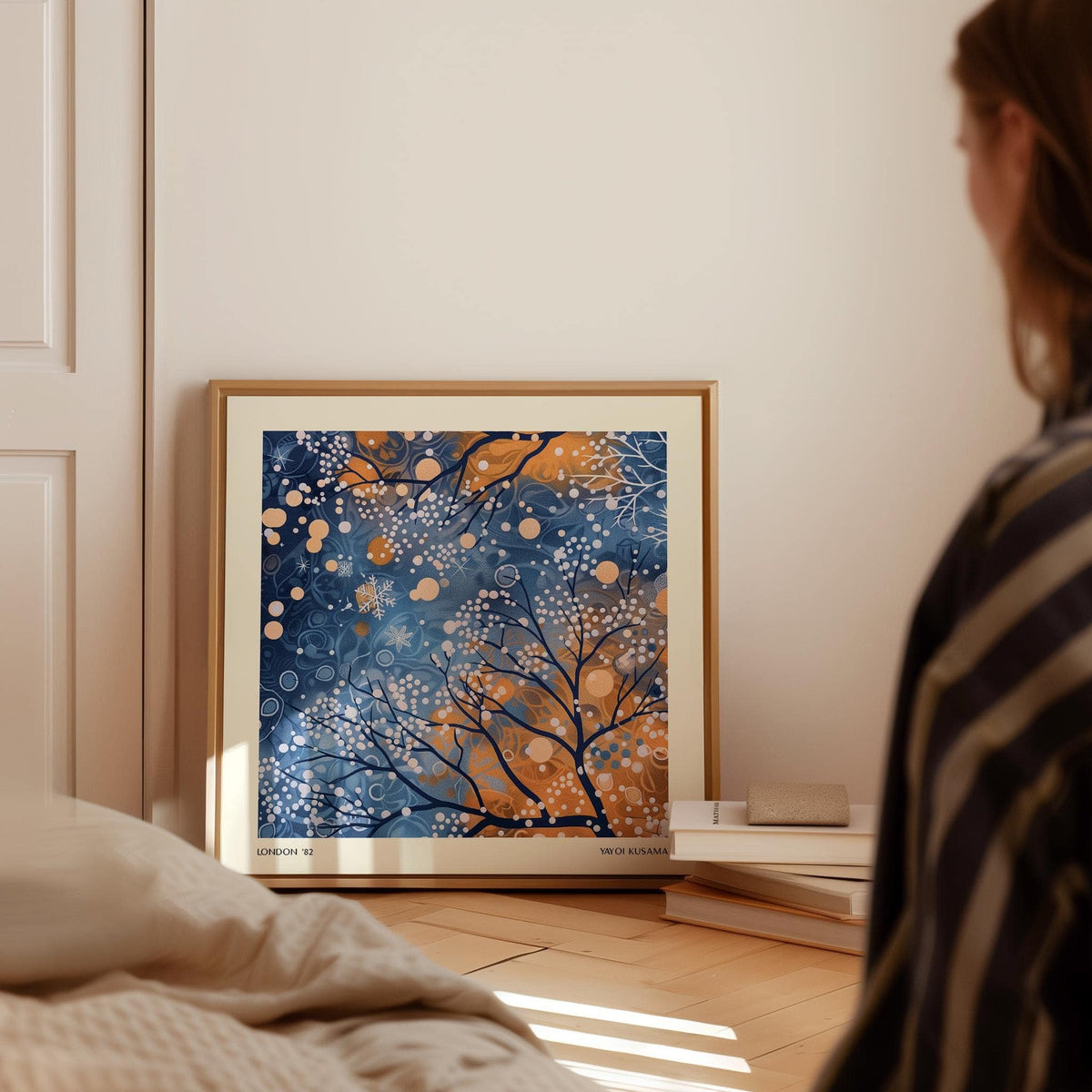 Winter Scene wall art leaning on a floor near books with blue and orange abstract branches
