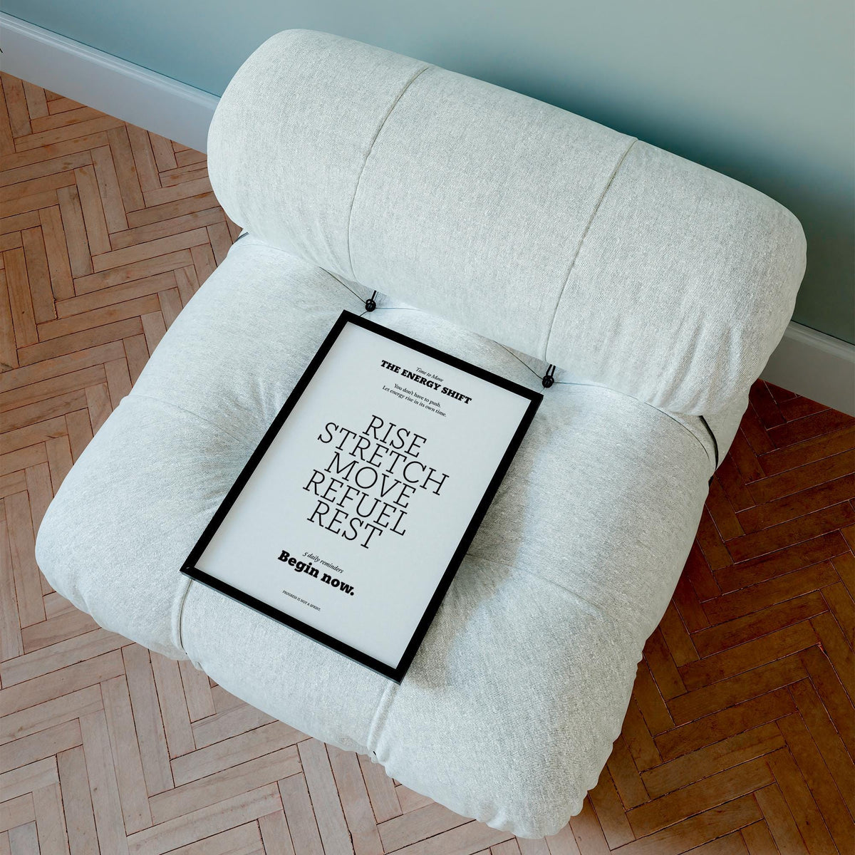 Framed posters with inspirational sayings on a white cushion chair with parquet flooring