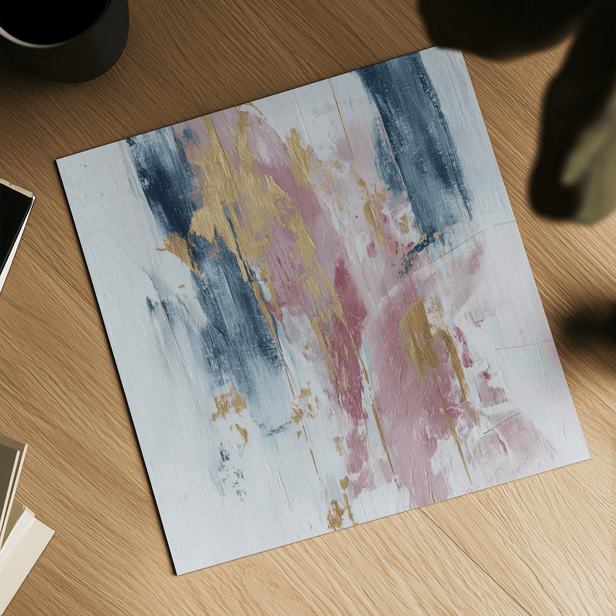 Pink Abstract Square Art close-up showing abstract paint strokes in pink navy and gold on a wooden surface with a black mug nearby