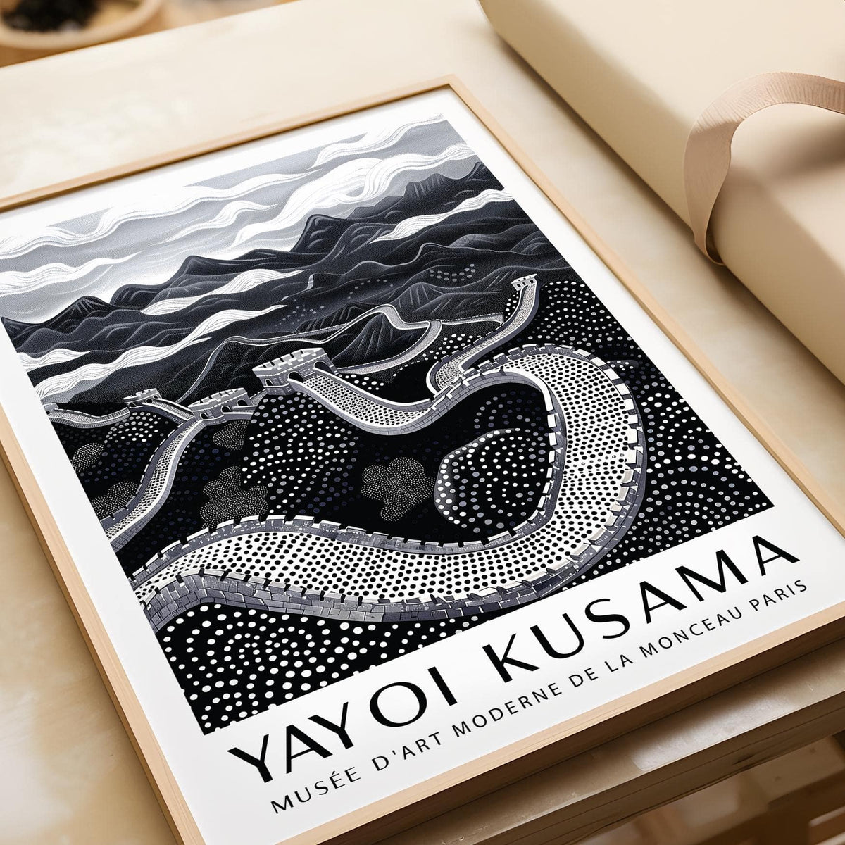 Framed Chinese wall art of the Great Wall in black white and grey on a table next to wrapping paper