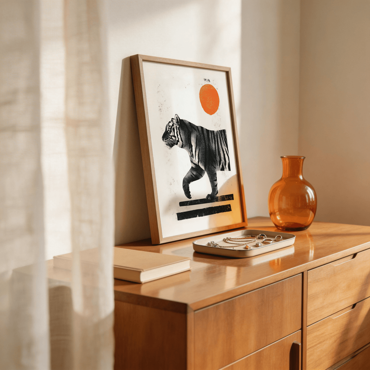 Print leaning on a wooden sideboard of an abstract black tiger with an orange sun and minimal colours with a tray and glass vase nearby