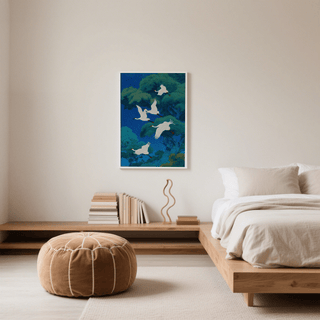 Bird Art Print of five flying white cranes against green trees on a blue background in a minimalist bedroom above a wooden shelf