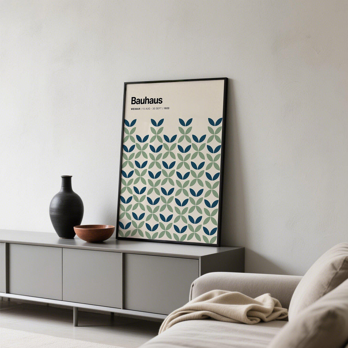 Print leaning on a console with blue and green geometric leaf pattern and black frame with decorative bowl