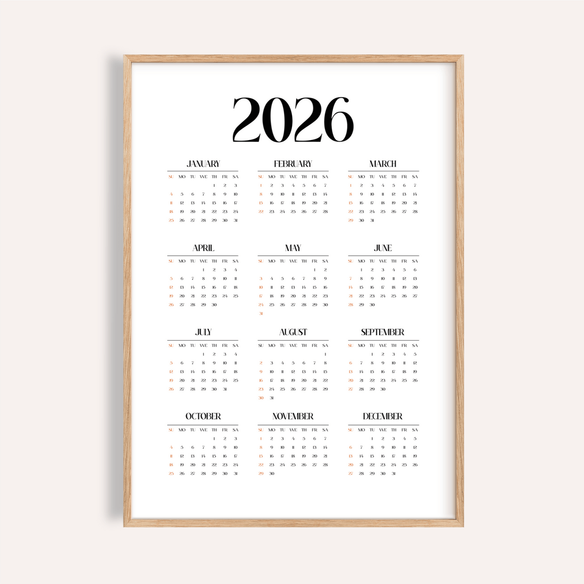 Minimalist wall calendar with black and orange text and numbers in a wood frame