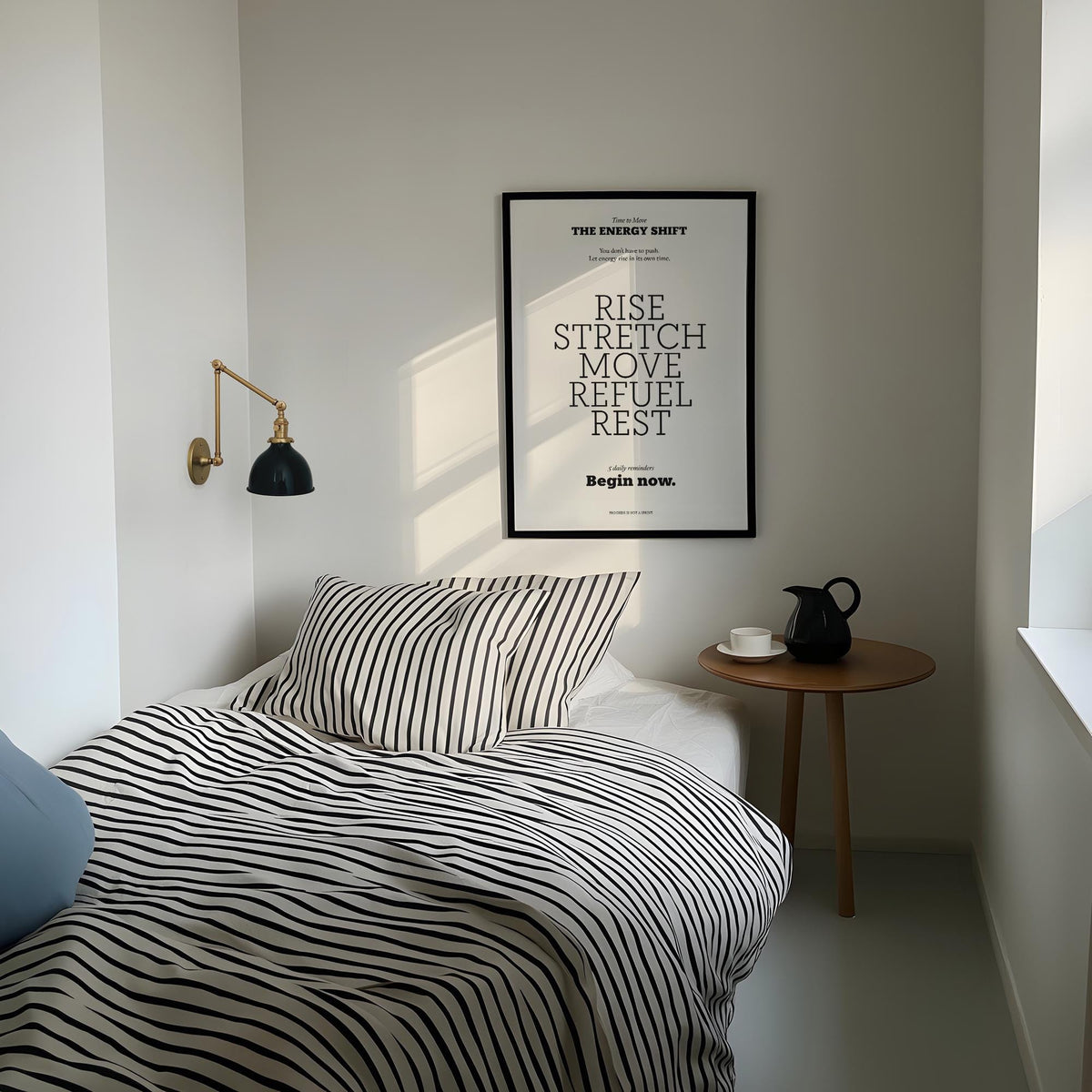 Posters with Inspirational Sayings framed print with motivational text in black and white above a bed with striped bedding and a wall lamp