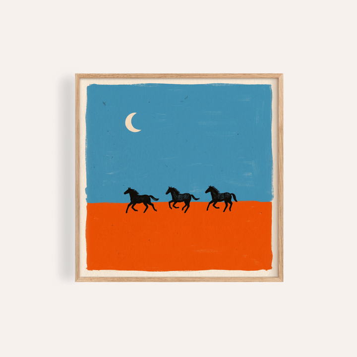 Framed horse silhouette wall art of three black horses running on an orange ground under a blue sky with a crescent moon