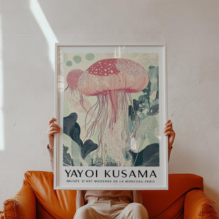 Framed print of sea animal wall art with a pink jellyfish and botanical details held above a brown leather sofa