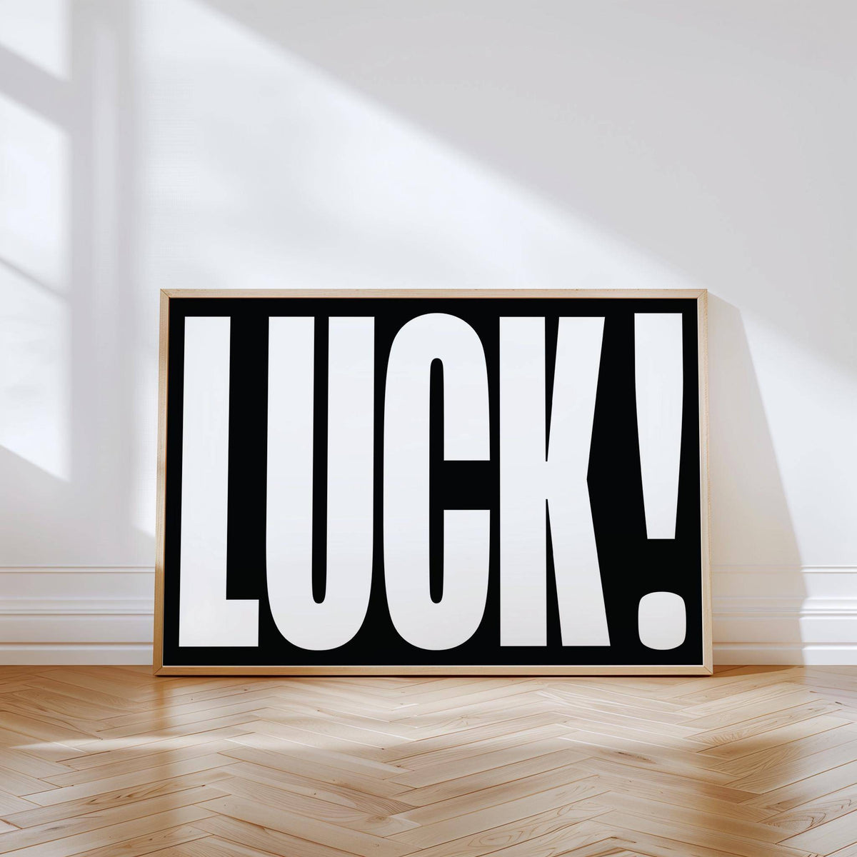 Lucky Gifts typographic wall art with white letters on black leaning against a white wall on a wooden floor