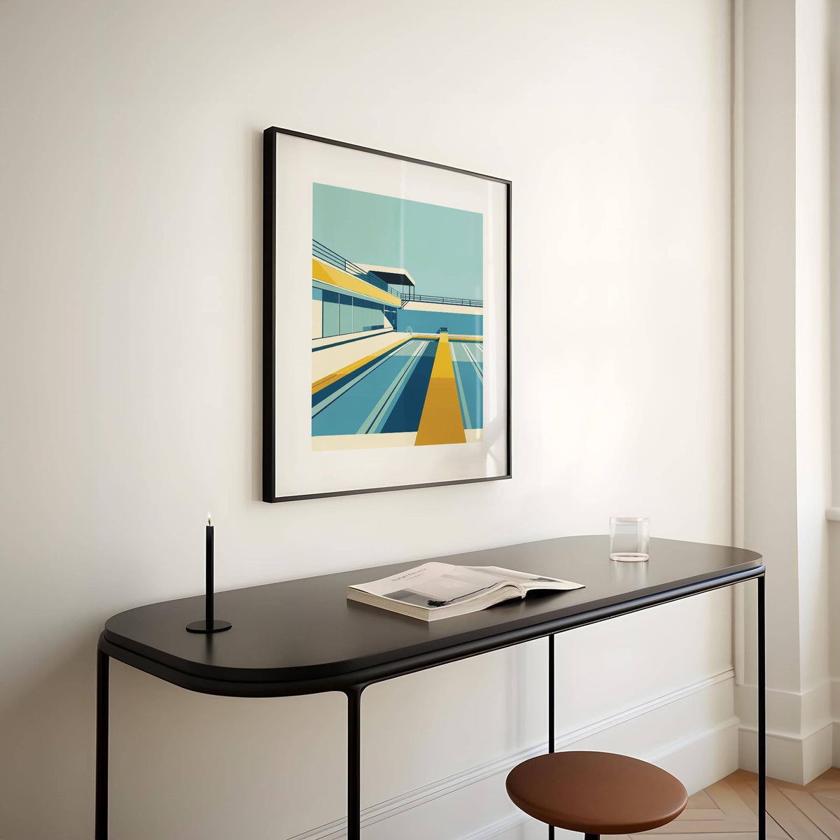 Pool print framed print on a light wall above a black console with a candle and open book
