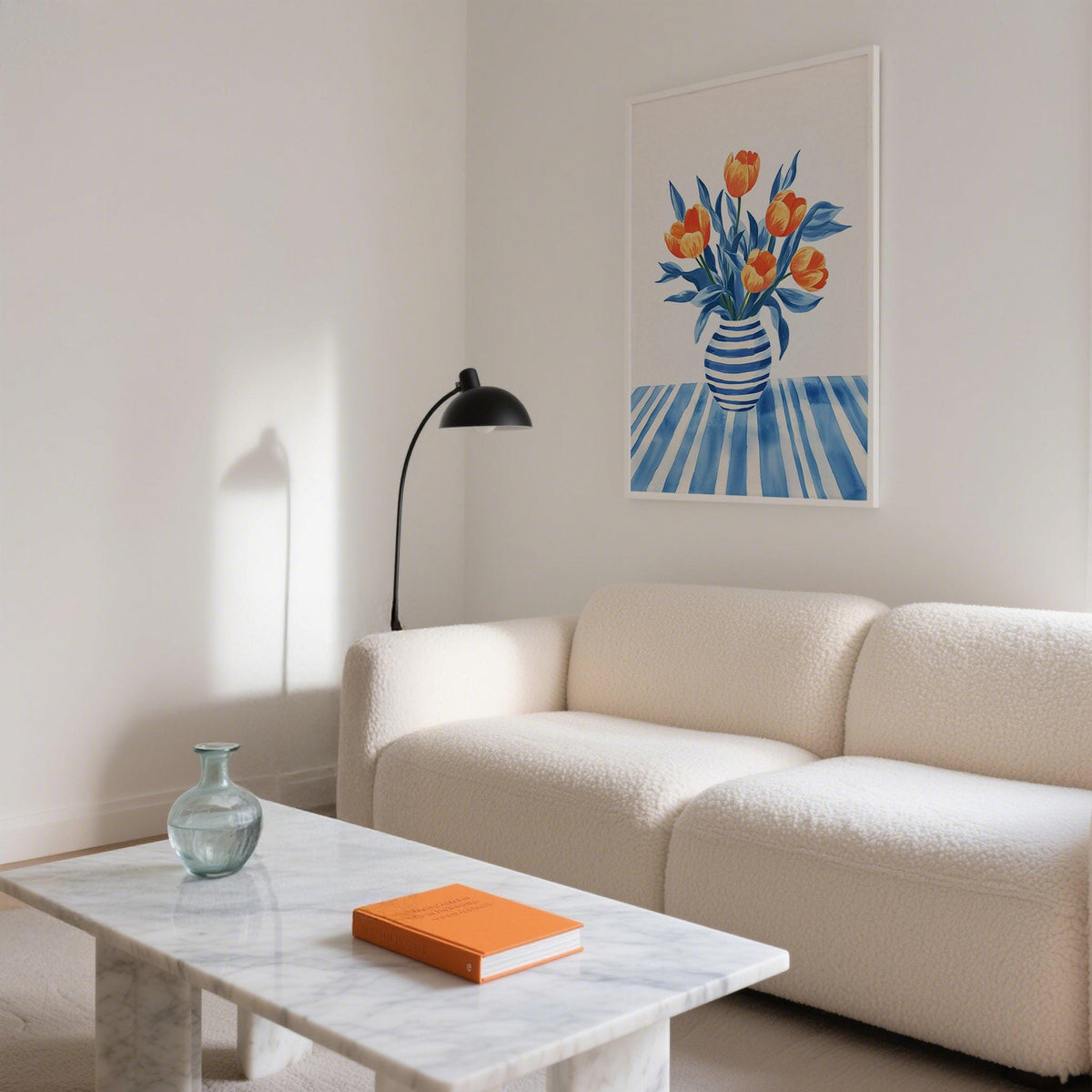 Tulip wall art with orange striped tulips and blue leaves above a white sofa with a black lamp