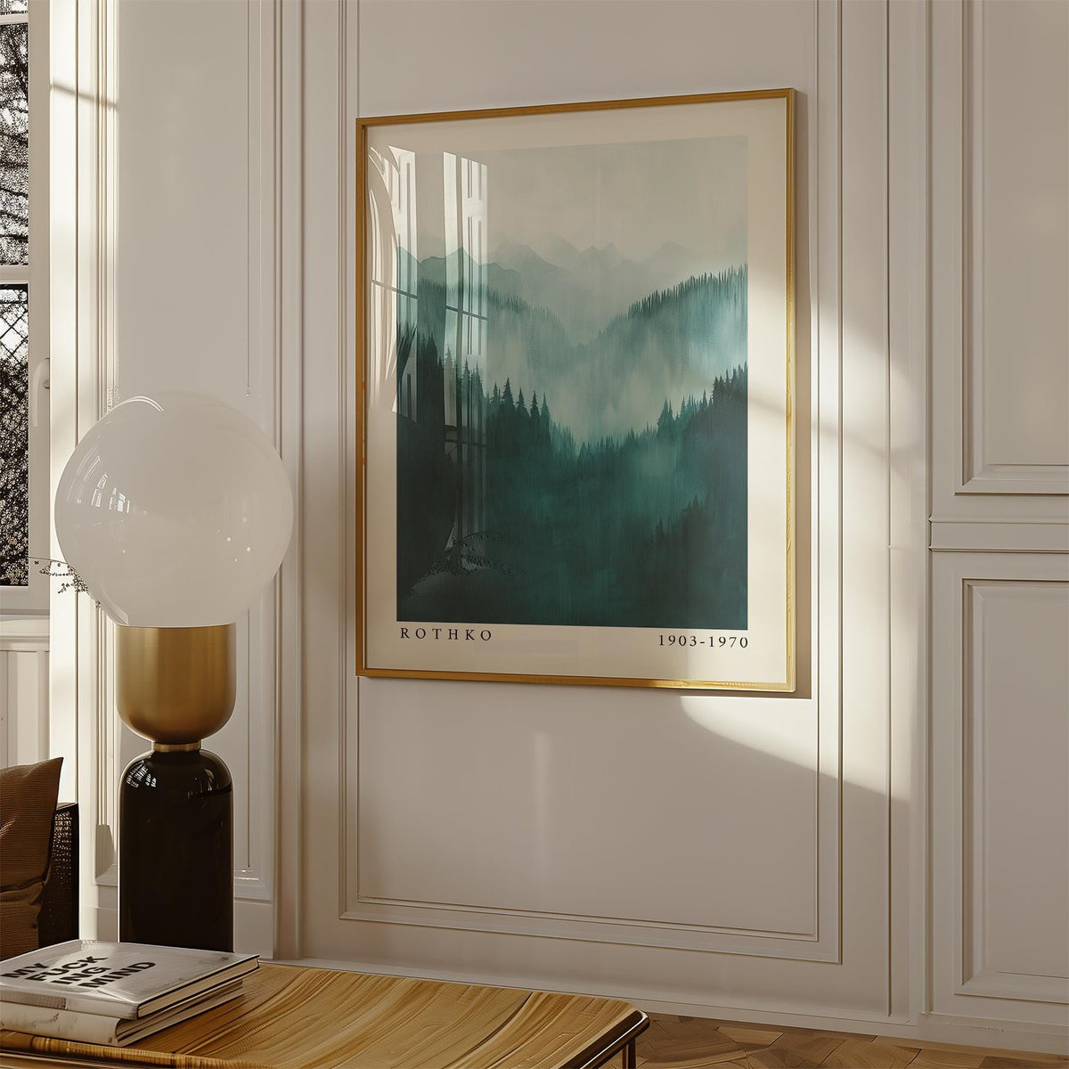 Mountain wall art of a misty green and blue mountain range above a wooden table with a lamp