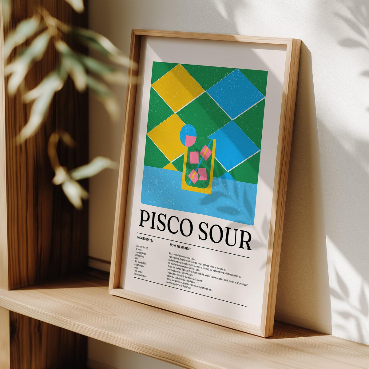 Print leaning on a shelf with abstract colorful Pisco Sour cocktail illustration and recipe text