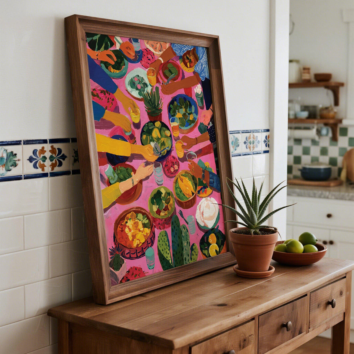 Framed Mexican Decor print of a group dining with food in bright colours on a wooden sideboard with a potted plant