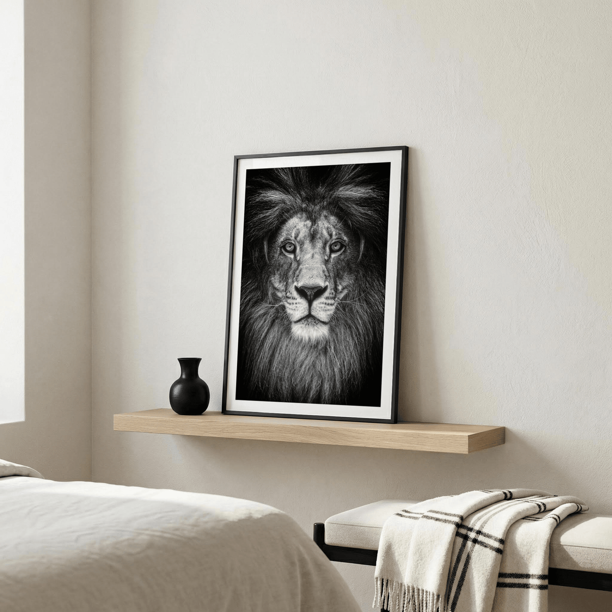 Black and white lion print leaning on a wooden shelf with a black vase in a bedroom