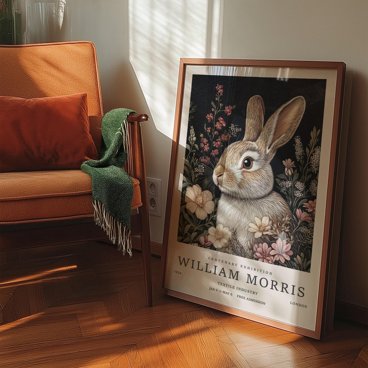 Print leaning on floor with vintage rabbit art of brown rabbit among pink flowers beside an orange chair