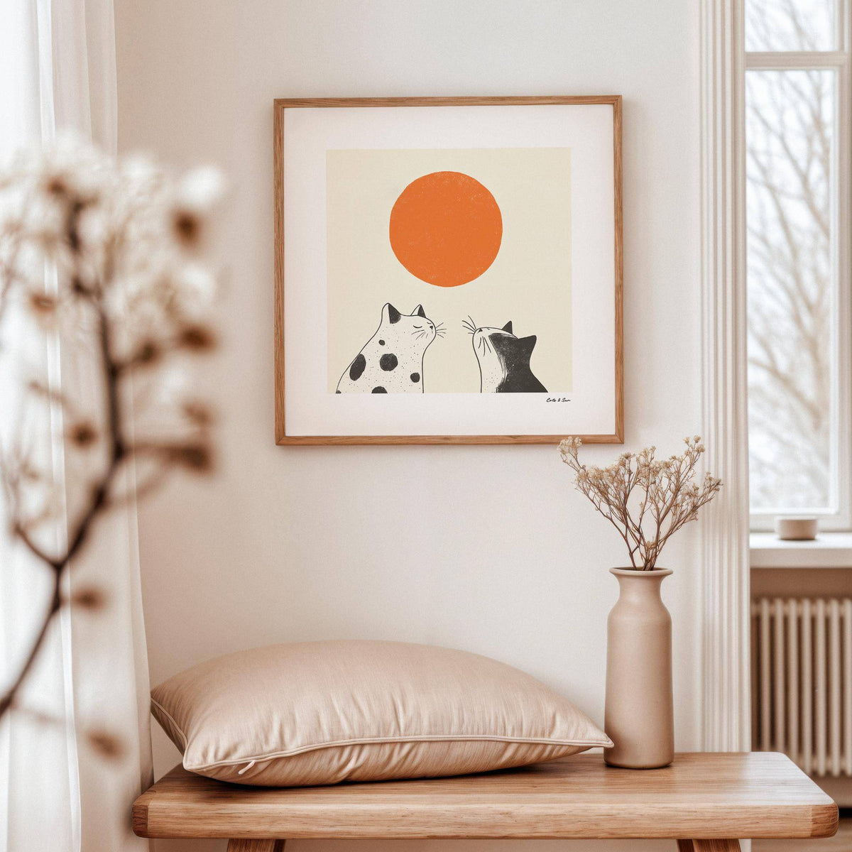 Orange Cat Art print of two black and white cats with an orange sun above a wooden table with a beige cushion