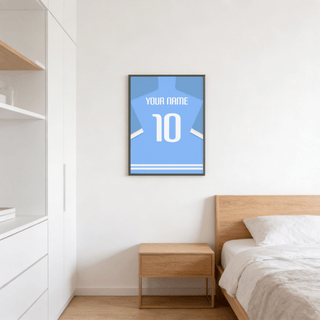 Football Shirt Poster in Light Blue with White Sleeve Stripes hung above a wooden bedside table in a bedroom