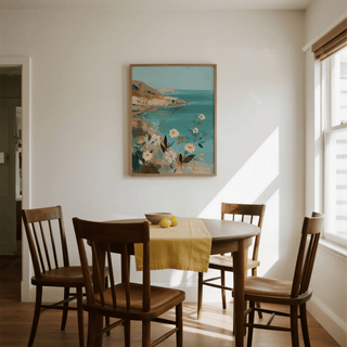 Floral Coast Print on a dining room wall showing coastal flowers in soft blues and earthy tones with a wooden table below