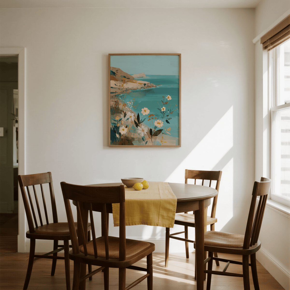 Floral Coast Print on a dining room wall showing coastal flowers in soft blues and earthy tones with a wooden table below