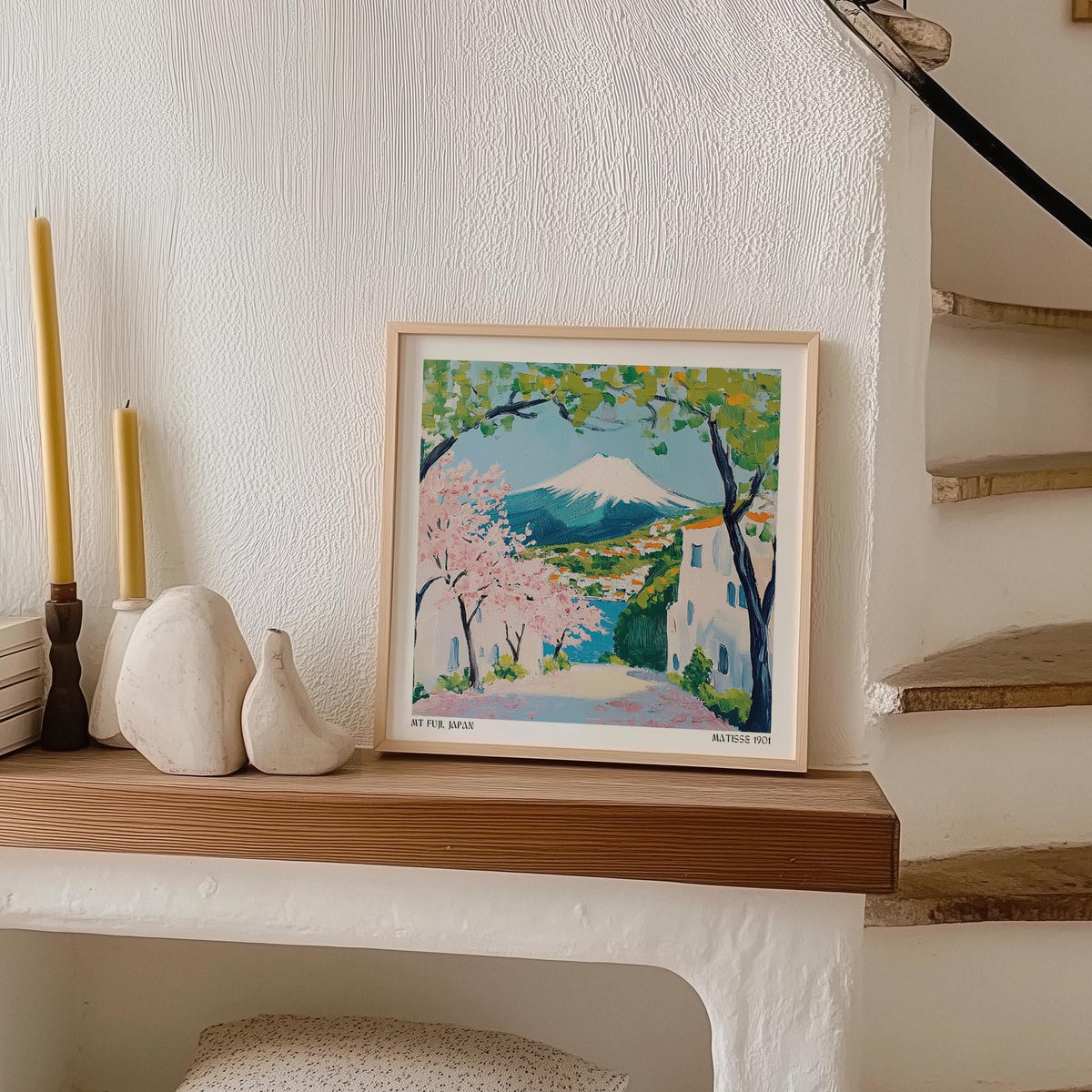 Japan Poster print of Mount Fuji with cherry blossoms leaning on a wooden shelf with yellow candles nearby