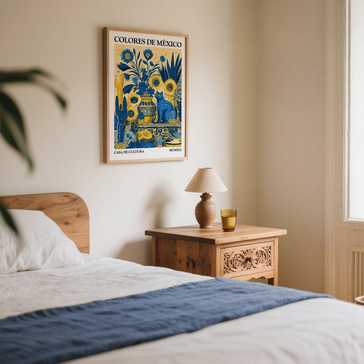 Otomi wall art with a blue cat and yellow sunflowers above a wooden bedside table in a bedroom