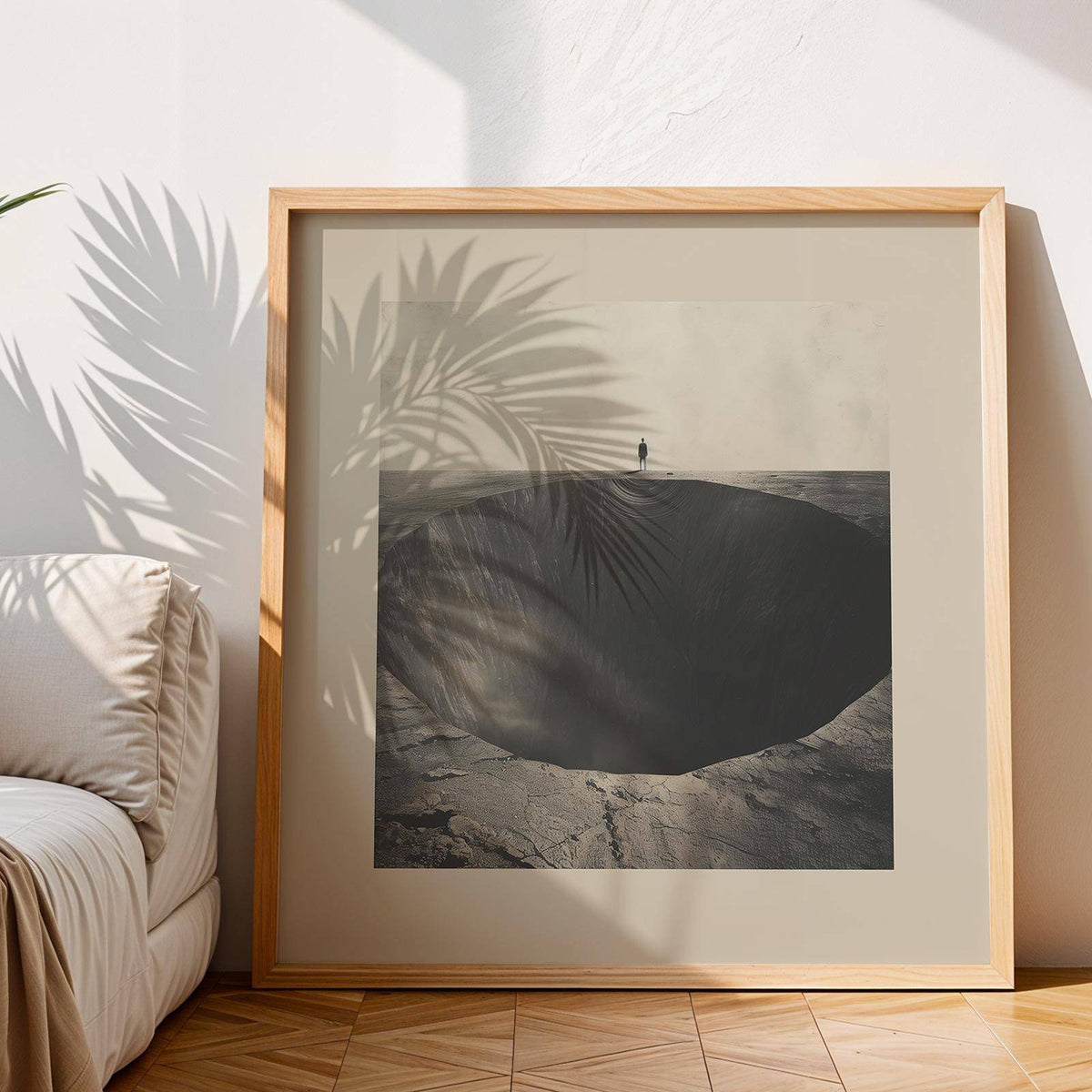 Framed Surrealist wall art of a large dark abyss hole with a small figure above it leaning on the floor beside a sofa